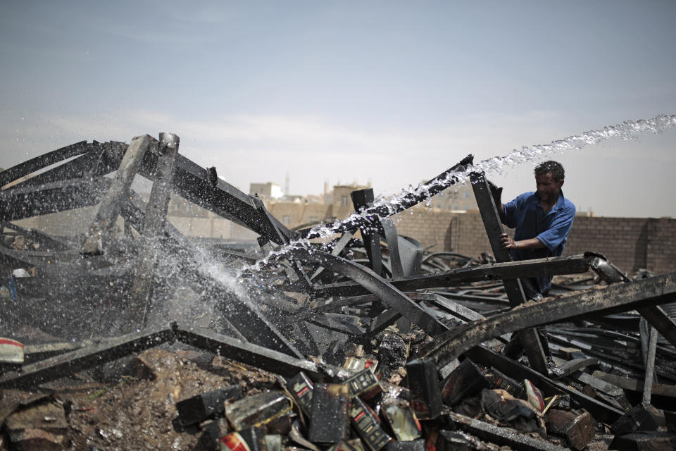 A worker uses a water hose to put down a fire at a vehicle oil store hit by Saudi-led airstrikes in Sanaa, Yemen, Thursday, July 2, 2020. (AP Photo/Hani Mohammed)