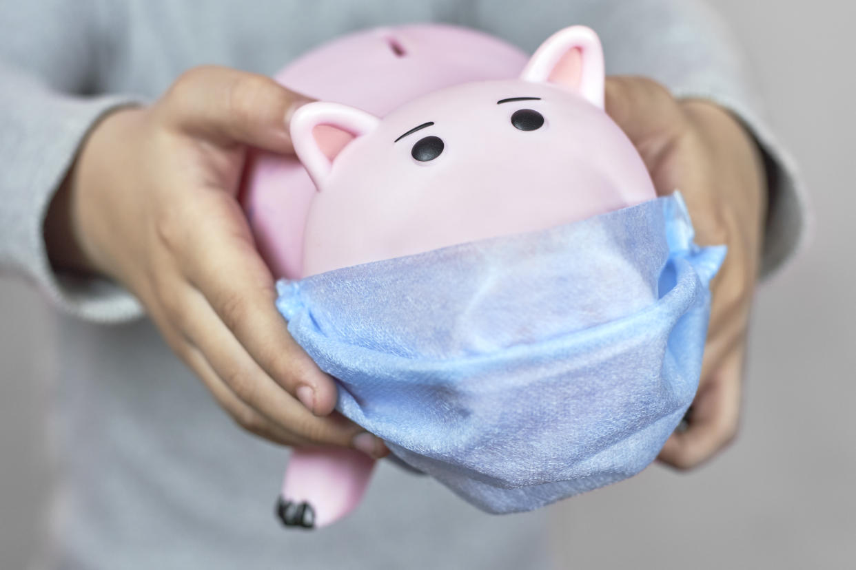 A little boy holding a piggy bank in face mask. Symbol of poor home budget. Personal Budgeting during the Coronavirus Pandemic. COVID-19 hurting family budget, savings and funds