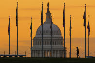 An early morning pedestrian is silhouetted against sunrise as he walks through the U.S. Flags on the National Mall and past the U.S. Capitol Building in Washington, Monday, Nov. 7, 2022, one day before the midterm election will determine the control of the U.S. Congress. (AP Photo/J. David Ake)