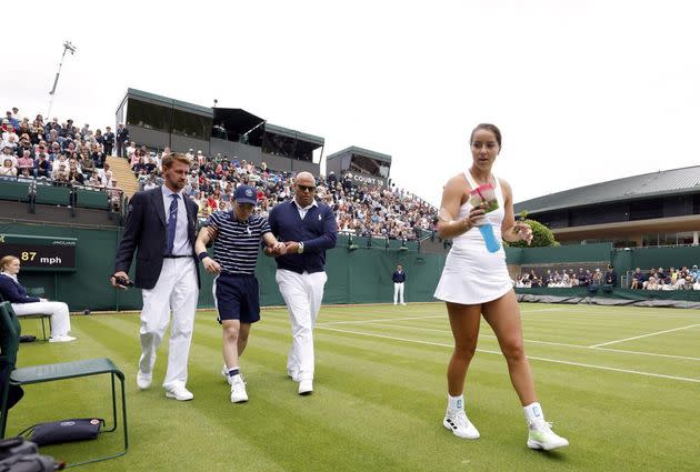 Britain's Jodie Burrage, right, walks back to her chair after giving a ball boy, second left, some refreshments after they fainted. (Photo: Steve Paston/PA via AP)