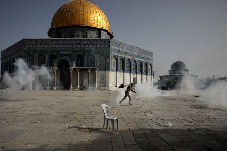 Un manifestante palestino corre entre el gas lacrimógeno lanzado por fuerzas de seguridad israelíes frente a la Cúpula de La Roca en el complejo de la Mezquita de Al-Aqsa, en Jerusalén