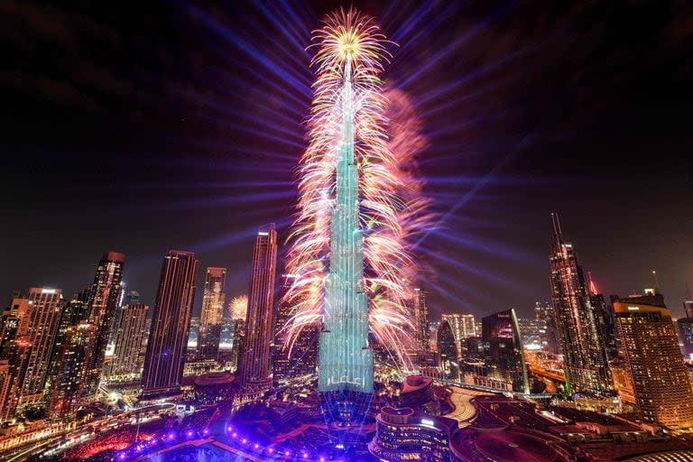 Los fuegos artificiales iluminan el cielo junto al emblemático rascacielos Burj Khalifa, el edificio más alto del mundo, en Dubai a medianoche en la víspera de Año Nuevo el 1 de enero de 2024