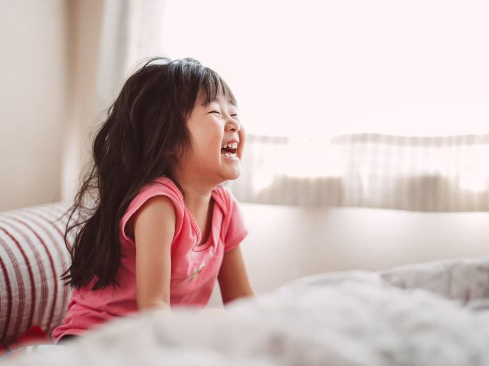 Little girl laughing joyfully in bed