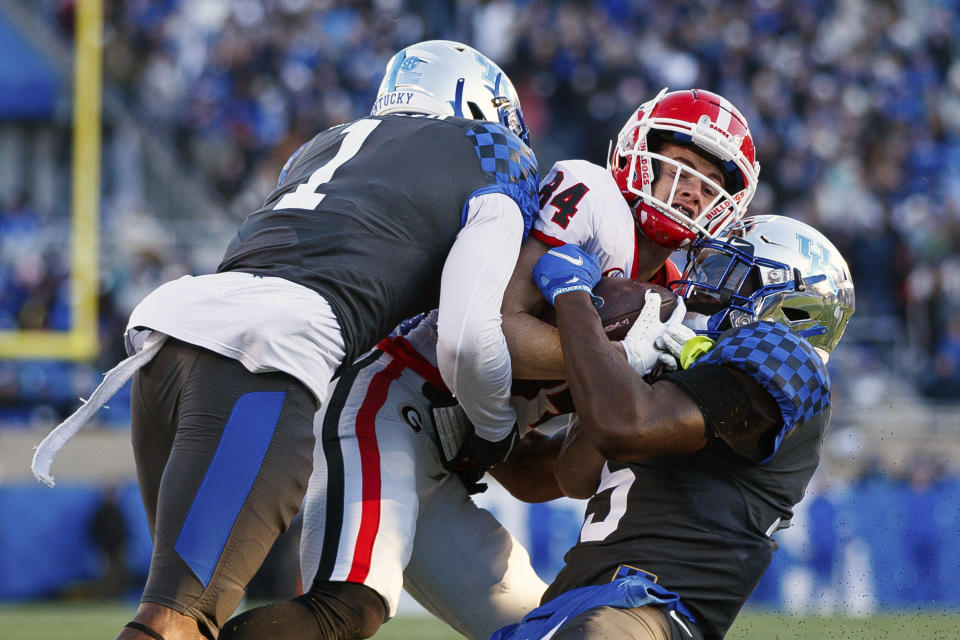 Kentucky defensive back Keidron Smith (1) and linebacker Jordan Wright, right, bring down Georgia wide receiver Ladd McConkey (84) during the first half of an NCAA college football game in Lexington, Ky., Saturday, Nov. 19, 2022. (AP Photo/Michael Clubb)