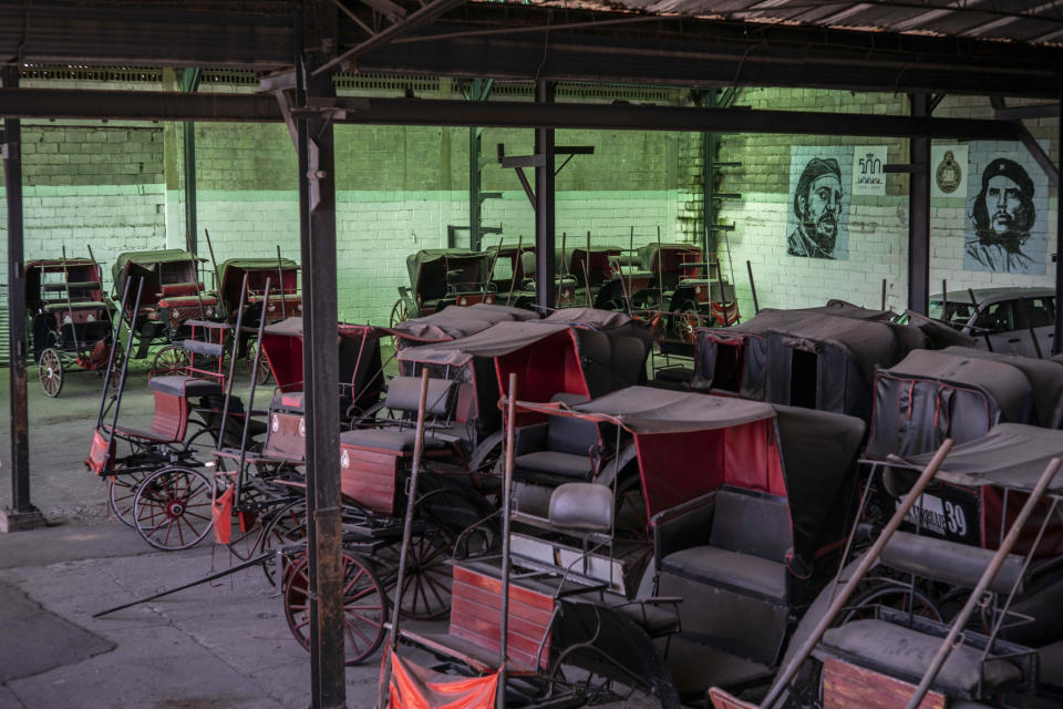 Horse carts used to give rides to tourists sit idle in the garage of a cooperative where murals of the late leader Fidel Castro and Revolutionary hero Ernesto "Che" Guevara cover the walls in Havana, Cuba, Feb. 24, 2021. "For everyone, Biden is hope," said Rigoberto Romero, owner of one of the carriages and who used to make a living by taking travelers around by horse-drawn carriage but now just takes care of his horses at home while tourism is down. (AP Photo/Ramon Espinosa)