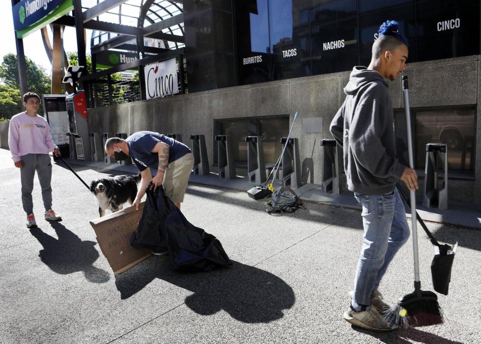 Robert Pintor, center, picks up a protest sign while son Tazio, 16, holds the family dog Remus and his friend Nico Card, 17, goes to sweep up litter along W. Broad St. June 1, 2020. Robert says he loves Columbus and wanted to help out by doing some clean up. Tazio was at the protests for the past three days.