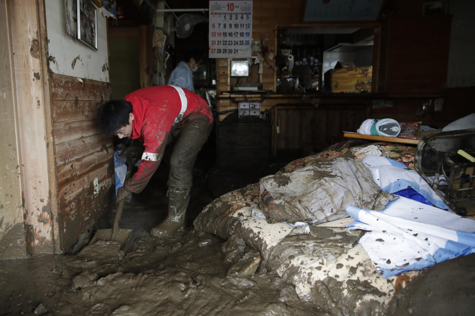 Yoshiki Yoshimura, 17, cleans up mud at his home after Typhoon Hagibis passed through the neighborhood, Tuesday, Oct. 15, 2019, in Nagano, Japan. More victims and more damage have been found in typhoon-hit areas of central and northern Japan, where rescue crews are searching for people still missing. (AP Photo/Jae C. Hong)