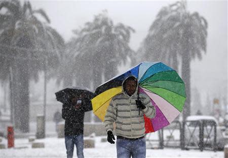 Men holding umbrellas walk outside Jerusalem's Old City during snowfall December 12, 2013. REUTERS/Darren Whiteside