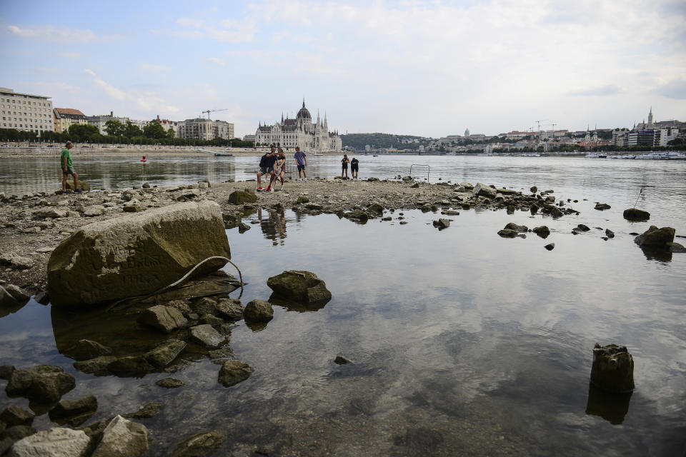 FILE - People take photos on the southern tip of Margaret Island, which can be seen due to low water level of the River Danube. in Budapest, Hungary, Tuesday, Aug. 9, 2022. An unprecedented drought is afflicting nearly half of the European continent, damaging farm economies, forcing water restrictions and threatening aquatic species. Water levels are falling on major rivers such as the Danube, the Rhine and the Po. (AP Photo/Anna Szilagyi, File)