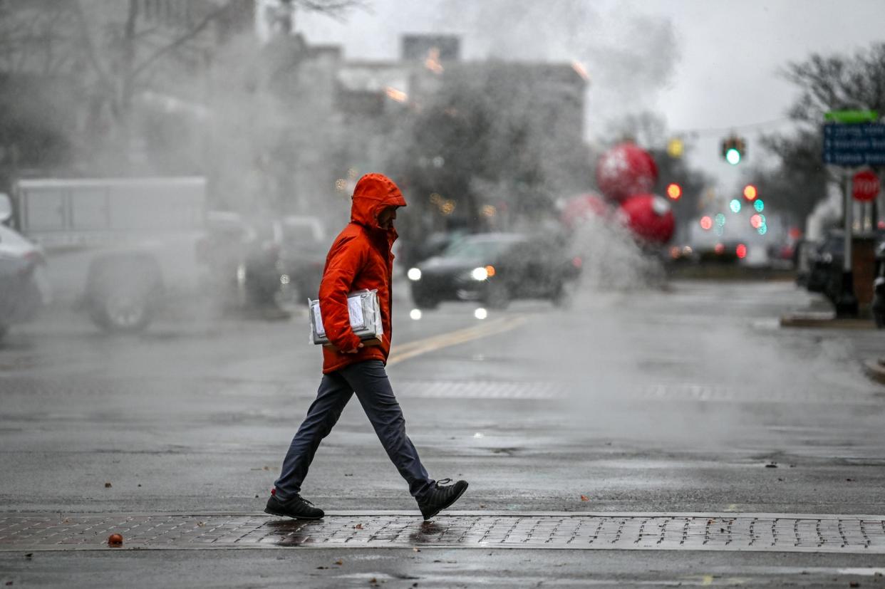 A pedestrian crosses Washington Square on a chilly, wet morning on Tuesday, Nov. 21, 2023, in downtown Lansing.