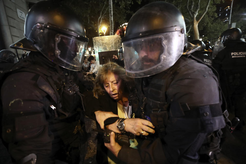 Los agentes escoltan a una mujer que pasaba por allí durante los enfrentamientos (AP Photo/Emilio Morenatti)