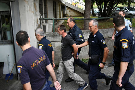 Alexander Vinnik, a 38 year old Russian man (C) suspected of running a money laundering operation using bitcoin, is escorted by police officers to the court in Thessaloniki, Greece, September 29, 2017. REUTERS/Alexandros Avramidis