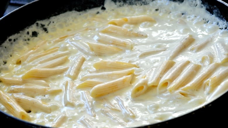 Closeup of pasta cooking with cream sauce in a pan
