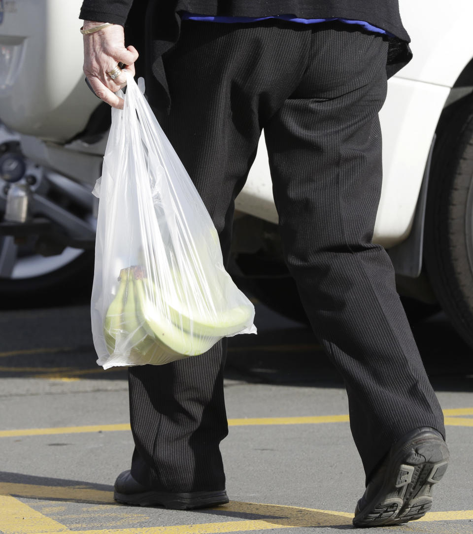 A shopper leaves a supermarket with goods in plastic bags in Christchurch, New Zealand, Friday, Aug. 10, 2018. New Zealand plans to ban disposable plastic shopping bags by next July as the nation tries to live up to its clean-and-green image. Prime Minister Jacinda Ardern said Friday that New Zealanders use hundreds of millions of the bags each year and that some of them end up polluting the precious coastal and marine environment. (AP Photo/Mark Baker)