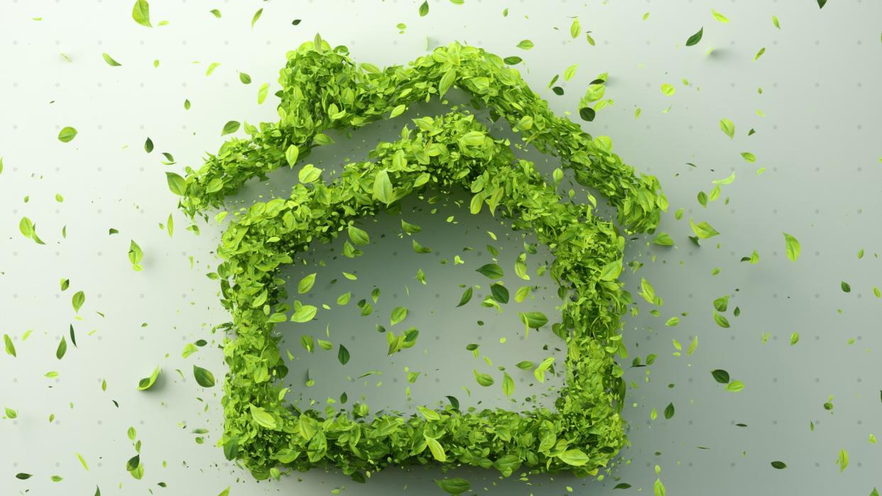  Green leaves arranged in the shape of a house on white background. 