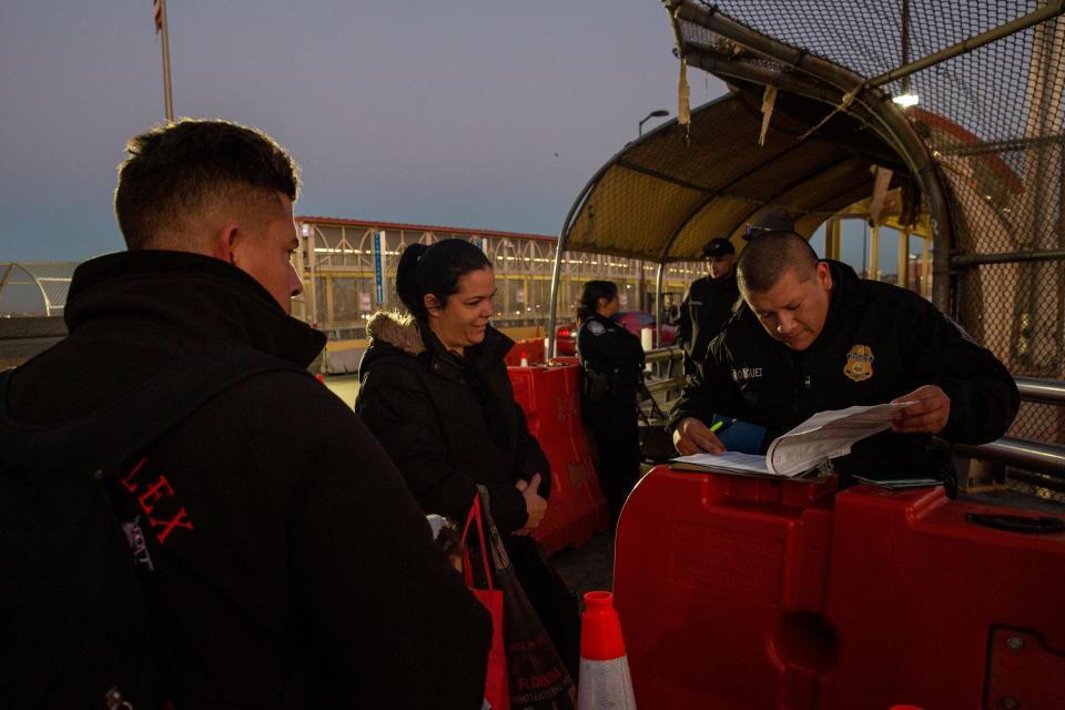 A Customs and Border Protection officer checks for the names of the Hernandez family at the Paso Del Norte International Bridge as they present themselves after receiving an appointment via the CPB One on Dec. 14, 2023.