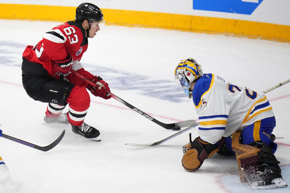 New Jersey Devils' Jesper Bratt, left, skates past Buffalo Sabres' Devon Levi during the NHL hockey game between Buffalo Sabres and New Jersey Devils, in Prague, Czech Republic, Saturday, Oct. 5, 2024. (AP Photo/Petr David Josek)