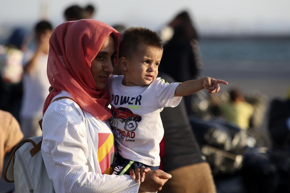 A migrant holds a boy upon their arrival at the port of Thessaloniki, northern Greece, Monday, Sept. 2, 2019. About 1,500 asylum-seekers were being transported from Greece's eastern Aegean island of Lesbos to the mainland Monday as part of government efforts to tackle massive overcrowding in refugee camps and a recent spike in the number of people arriving from the nearby Turkish coast. (AP Photo/Giannis Papanikos)