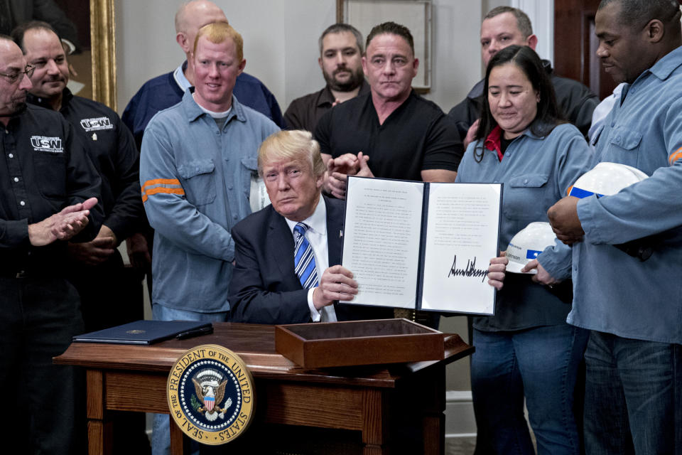 President Trump holds up a signed proclamation on adjusting tariffs on imports of steel into the United States, flanked by steel and aluminum workers in the Roosevelt Room of the White House on March 8, 2018. (Photo: Andrew Harrer/Bloomberg via Getty Images)