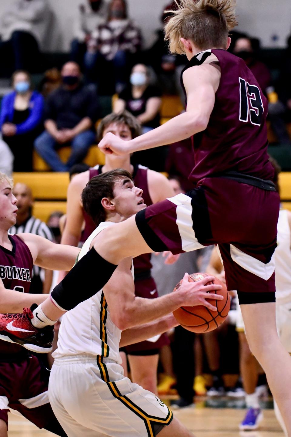 Buhler's Wade Meyer (13) goes airborne as Salina South forward Zach Davidson (14) looks for a shot under the basket Thursday night in a first-round Salina Invitational Tournament game at the South gym.