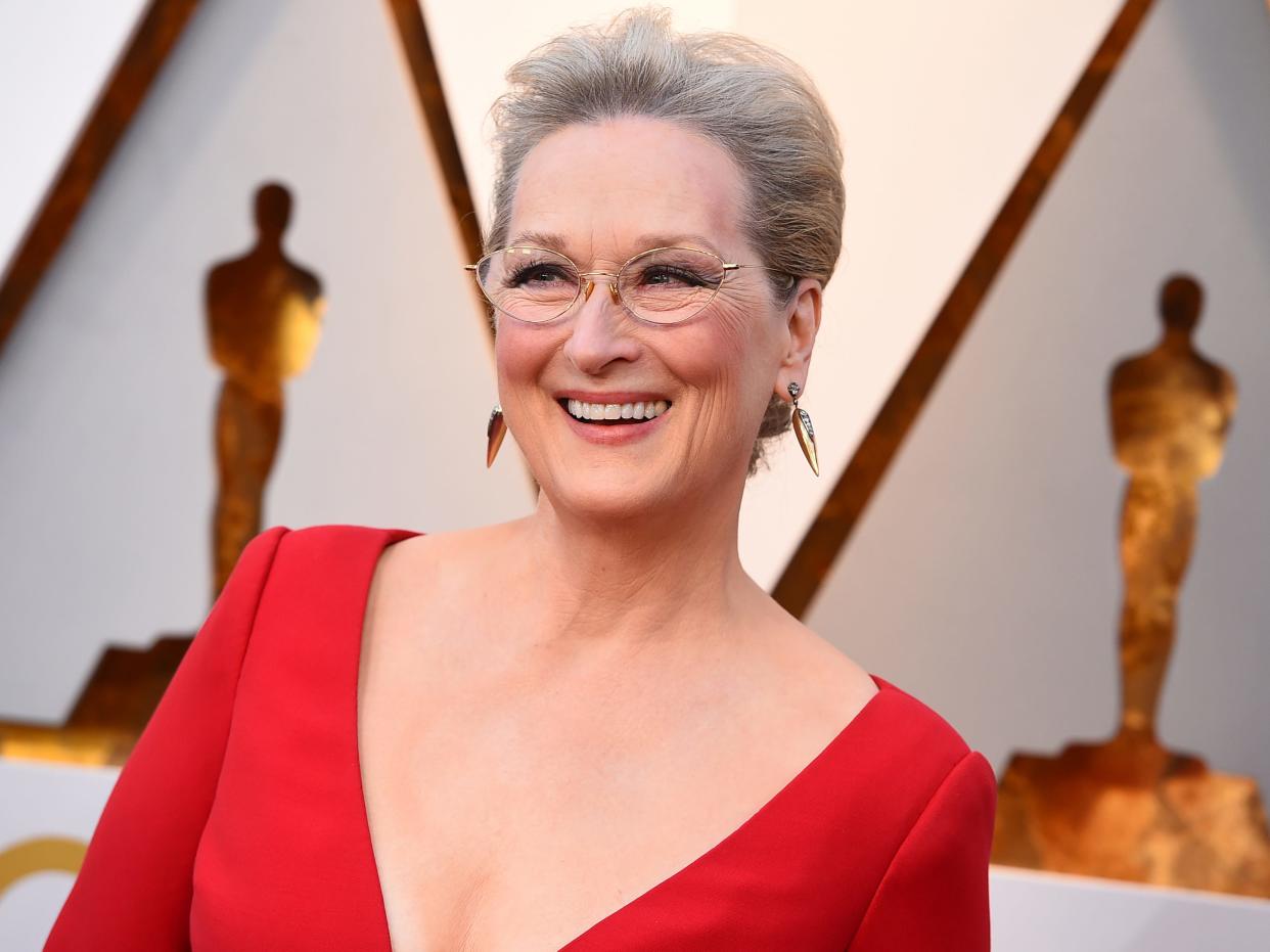 Meryl in a red plunging neck dress and glasses.