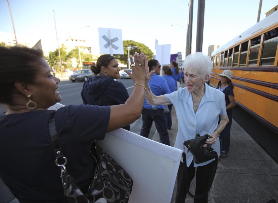 Mary Koning slaps a high five to Ivette Lopez after she arrived to support a rally against same sex marriage at the Hawaii State Capital in Honolulu