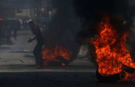 A Palestinian protester stands next to burning tyres during clashes with Israeli troops near Qalandiya checkpoint near the West Bank city of Ramallah July 21, 2017. REUTERS/Mohamad Torokman