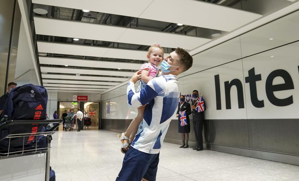 Olympic gymnast Max Whitlock hugs his daughter Willow as he arrives back at London Heathrow Airport (Steve Parsons/PA) (PA Wire)