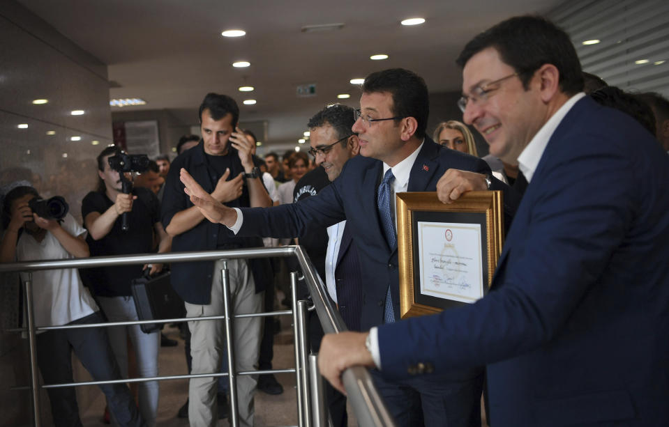 Ekrem Imamoglu, the candidate of Turkey's main opposition Republican People's Party, center, reacts to cheering supporters after he received a certificate confirming his election victory, in Istanbul, Thursday, June 27, 2019. Imamoglu is formally taking office as mayor of Istanbul four days after he won a repeat election in Turkey's largest city and commercial hub. (Imamoglu Team via AP, Pool)