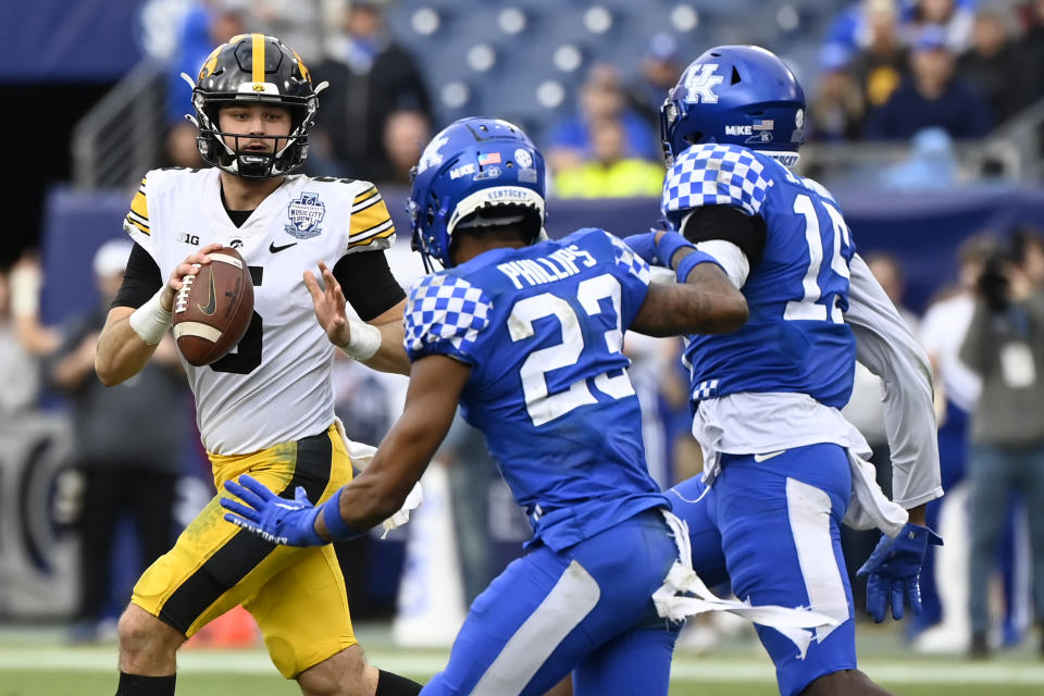 Iowa quarterback Joe Labas (5) looks to pass as Kentucky defensive back Andru Phillips (23) and linebacker Jordan Wright (15) move in during the the second half of the Music City Bowl NCAA college football game, Saturday, Dec. 31, 2022, in Nashville, Tenn. Iowa won 21-0. (AP Photo/Mark Zaleski)