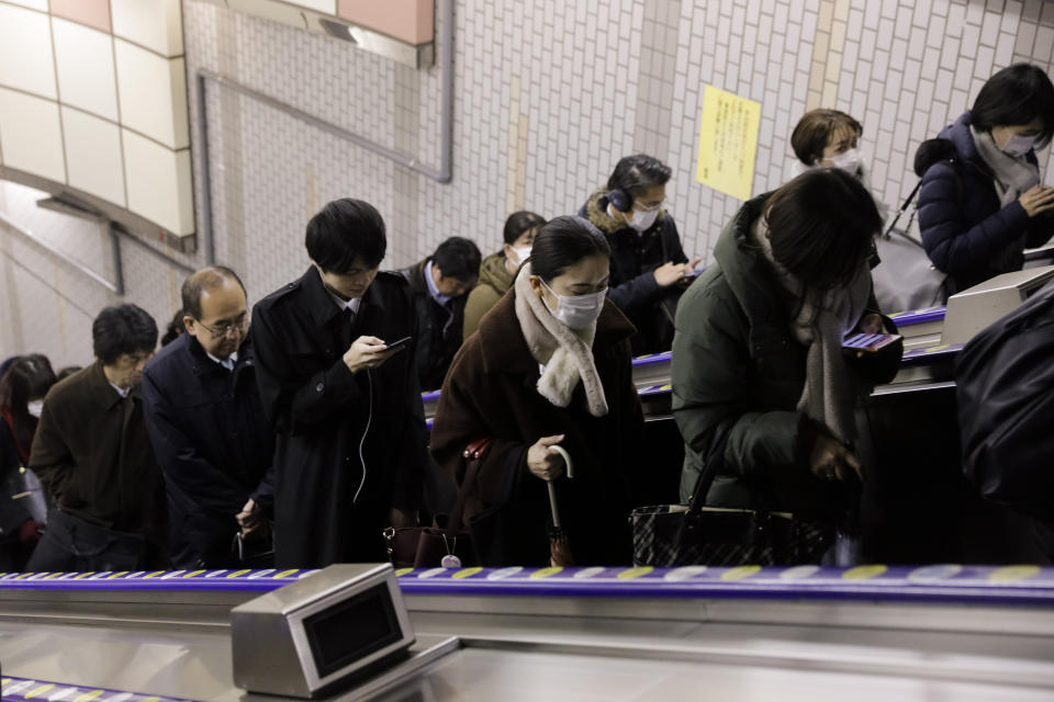 Commuters, some with masks on, ride an escalator to exit a train station during morning rush hours Tuesday, Jan. 28, 2020, in Tokyo. China on Tuesday reported 25 more deaths from a new viral disease as the U.S. government prepared to evacuate Americans from the city at the center of the outbreak. Japan, Mongolia, France and other governments also were preparing evacuations. (AP Photo/Jae C. Hong)