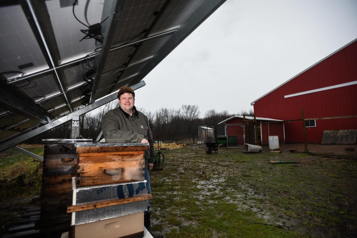 Troy Stroud, 52, of Eagle Township near beehives under his solar panels at his small farm on Bauer Road, Wednesday, April 5, 2023.