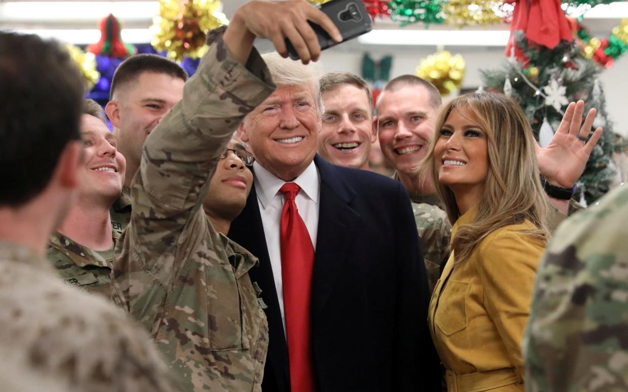 Donald Trump and Melania posing for selfies with US troops during a surprise visit to Iraq - REUTERS