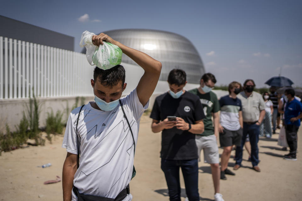 A man cools his head with an ice bag waiting to be vaccinated against Covid-19 at the Isabel Zendal Hospital in Madrid, Spain, Tuesday, July 20, 2021. Spain is trying to stamp out a new wave of COVID-19 among its youth thanks to a robust vaccination program that is widely supported. Spain like the rest of the European Union got off to a slow start to compared to the United States and Britain when the first vaccines were released. But it has quickly made up ground once deliveries by drug makers started flowing. (AP Photo/Olmo Calvo)