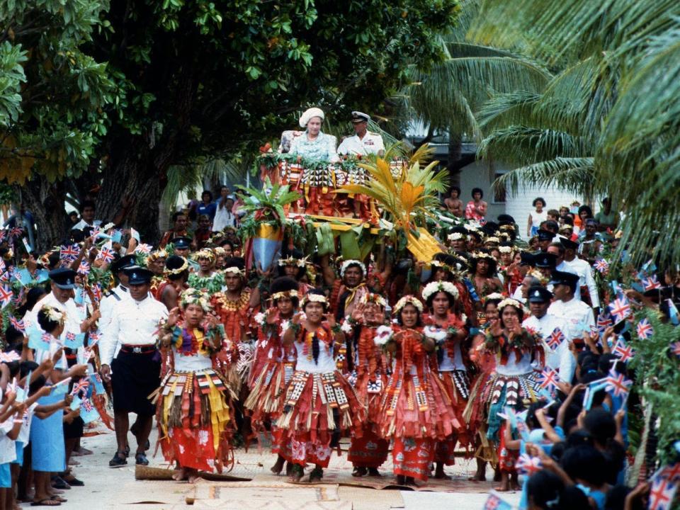 Queen Elizabeth ll and Prince Philip are carried in war canoes down the main street in Tuvalu during a tour of the South Pacific on October 27, 1982.