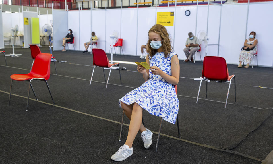 Gloria Raudjarv, 13-year-old girl, reads her vaccination certificate after getting an injection resting at a vaccination center inside a sports hall in Estonia's second largest city, Tartu, 164 km. south-east from Tallinn, Estonia, Thursday, July 29, 2021. Estonia's second largest city Tartu is making rapid progress in vaccinating children aged 12-17 ahead of the school year in September. Around half of the town's teenagers have already received their first vaccine, and local health officials are confident they will hit 70% in the coming 30 days. (AP Photo/Raul Mee)