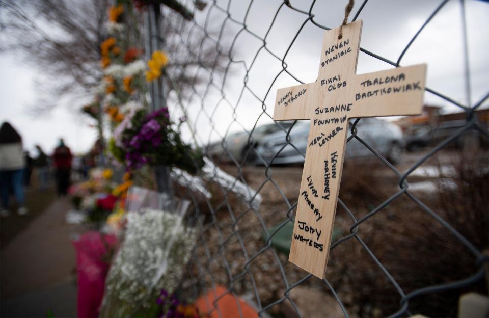 A cross with the names of the victims of a mass shooting at King Soopers hangs from a fence at a memorial outside the store in Boulder, Colo., on  March 23, 2021.