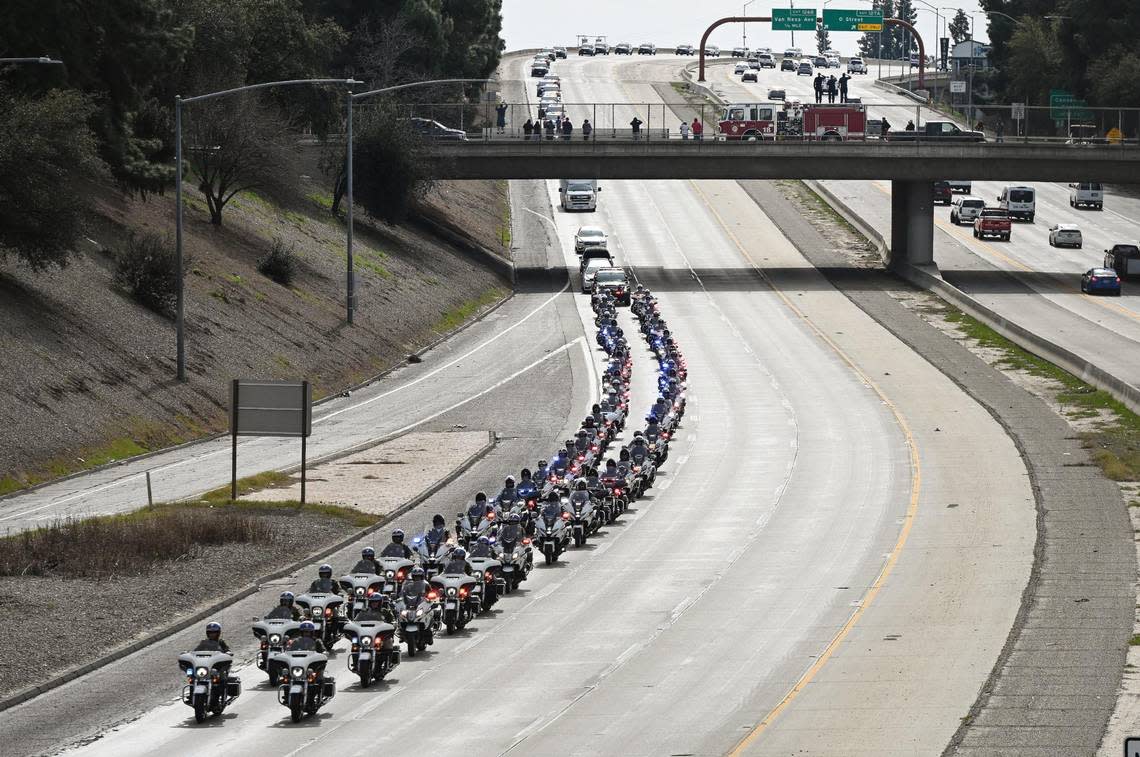 A motorcade of police motorcycles escorts a hearse containing officer Gonzalo Carrasco Jr.’s casket north on Highway 41 in downtown Fresno as officers from around the state follow in a police procession toward Reedley for burial following a funeral service at Selland Arena on Thursday, Feb. 16, 2023.