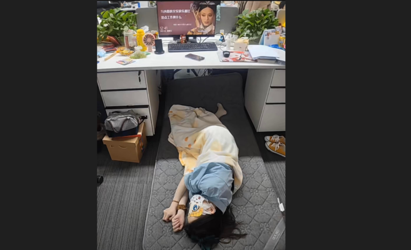 一名女性上班族把辦公室當自家，直接在辦公桌下鋪睡墊、蓋被子、戴眼罩午睡。（翻攝《爆廢公社公開版》） 
