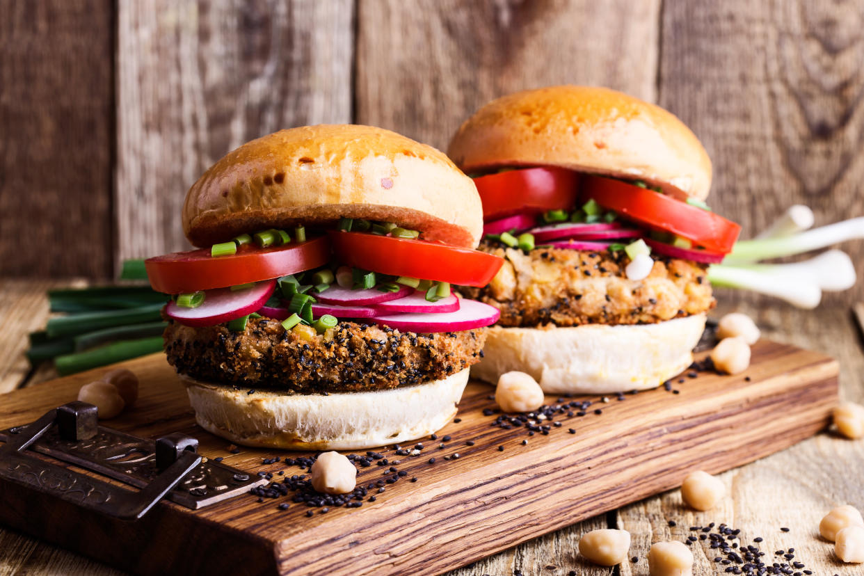 Vegan meal. Chickpea veggie burger with fresh vegetables on rustic cutting board