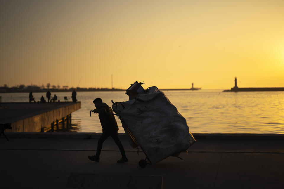 A garbage collector pulls a trolley full of cardboards at Kadikoy ferry terminal, in Istanbul, Turkey, Monday, March 4, 2024. (AP Photo/Francisco Seco)