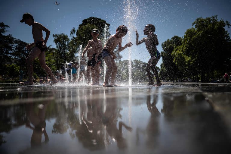 Chicos se refrescan en una fuente en Nantes. (Photo by Loic VENANCE / AFP)