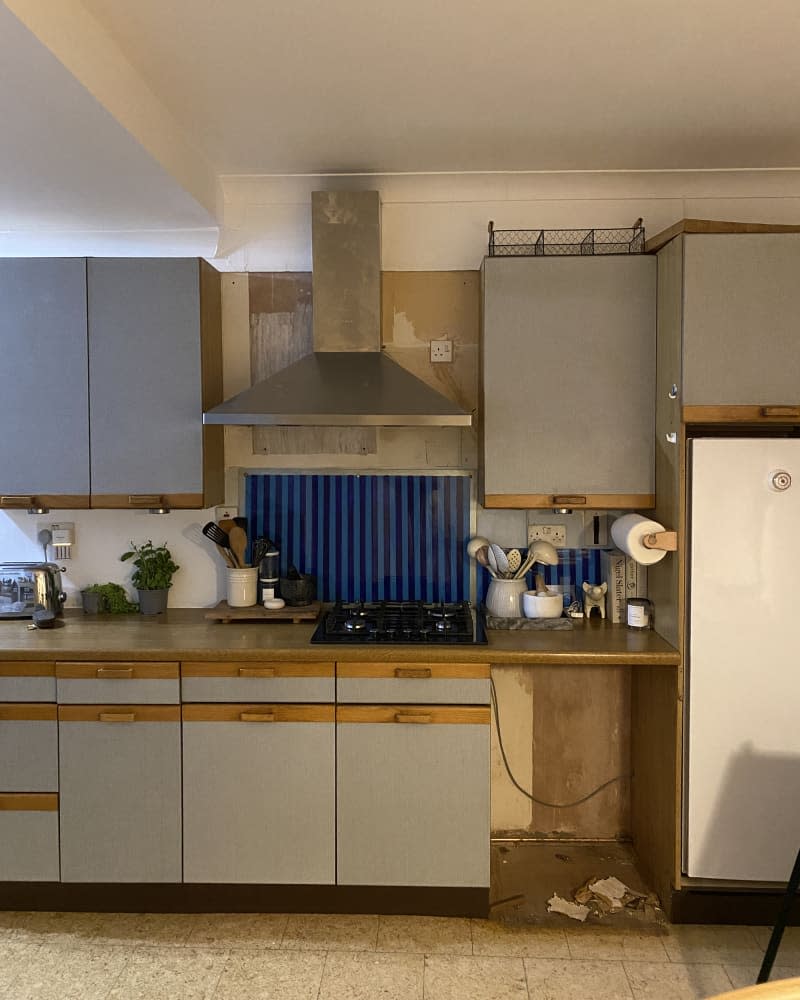 outdated smoke-stained kitchen with gray cabinets and white and blue tile backsplash before remodel