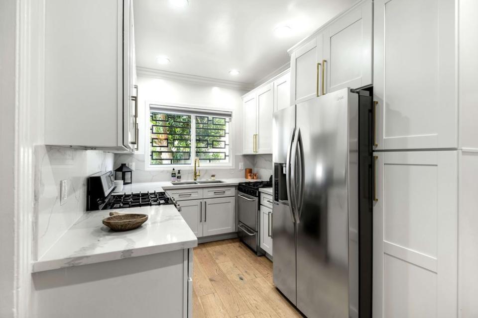 6) Here's the kitchen with marble countertops and white cabinets.