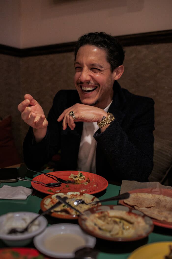 A smiling man enjoys the food at a Lebanese restaurant.