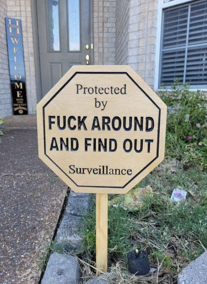 Sign in front of a house reads "Protected by F*** Around and Find Out Surveillance" with humorous intent