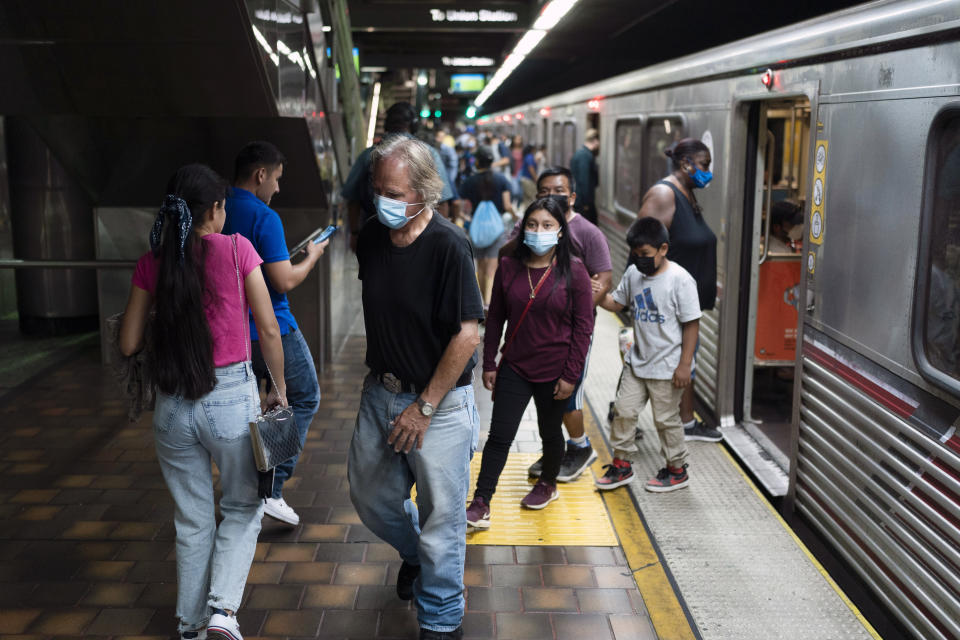 Masked and unmasked commuters are seen at a Metro station in Los Angeles, Wednesday, July 13, 2022. Los Angeles County, the nation's largest by population, is facing a return to a broad indoor mask mandate if current trends in hospital admissions continue, health director Barbara Ferrer told county supervisors Tuesday. (AP Photo/Jae C. Hong)