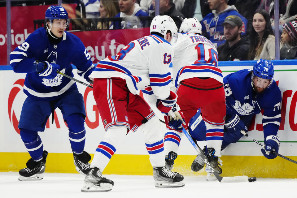 New York Rangers' Alexis Lafreniere (13) takes the puck as Toronto Maple Leafs' TJ Brodie (78) is checked by Rangers' Vincent Trocheck (16) and Maple Leafs' Tyler Bertuzzi (59) looks on during second-period NHL hockey game action in Toronto, Saturday, March 2, 2024. (Frank Gunn/The Canadian Press via AP)