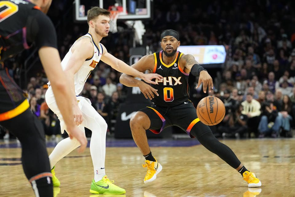 Phoenix Suns guard Jordan Goodwin (0) passes the ball as Denver Nuggets guard Christian Braun defends during the first half of an NBA basketball game, Friday, Dec. 1, 2023, in Phoenix. (AP Photo/Matt York)