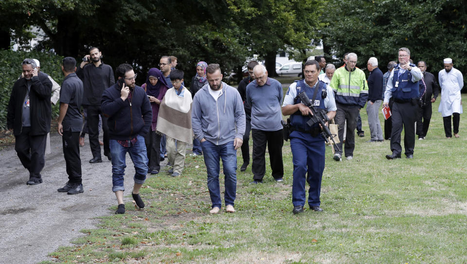 FILE - in this March 15, 2019, file photo, Len Peneha, left, walks with survivors as he is escorted by police away from the Al Noor mosque following the mass shooting in central Christchurch, New Zealand. New Zealanders on Sunday, March 15, 2020, will commemorate those who died on the first anniversary of the mass killing, as the tragedy continues to ripple through the community. Three people whose lives were forever altered that day say it has prompted changes in their career aspirations, living situations and in the way that others perceive them. (AP Photo/Mark Baker,File)